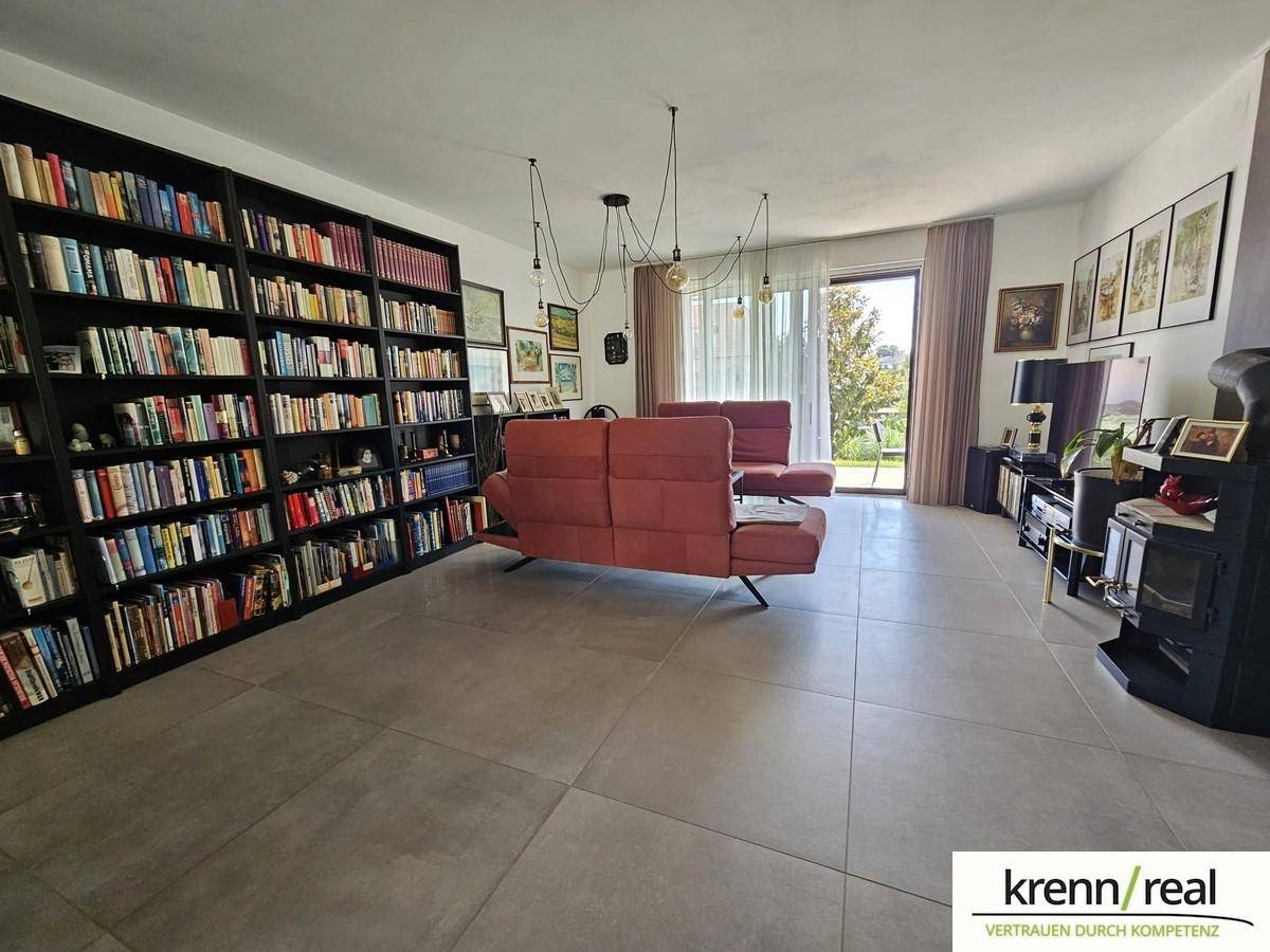 Gemütliches Wohnzimmer mit umfangreicher Bibliothek, bequemer Couch und Zugang zum Außenbereich.