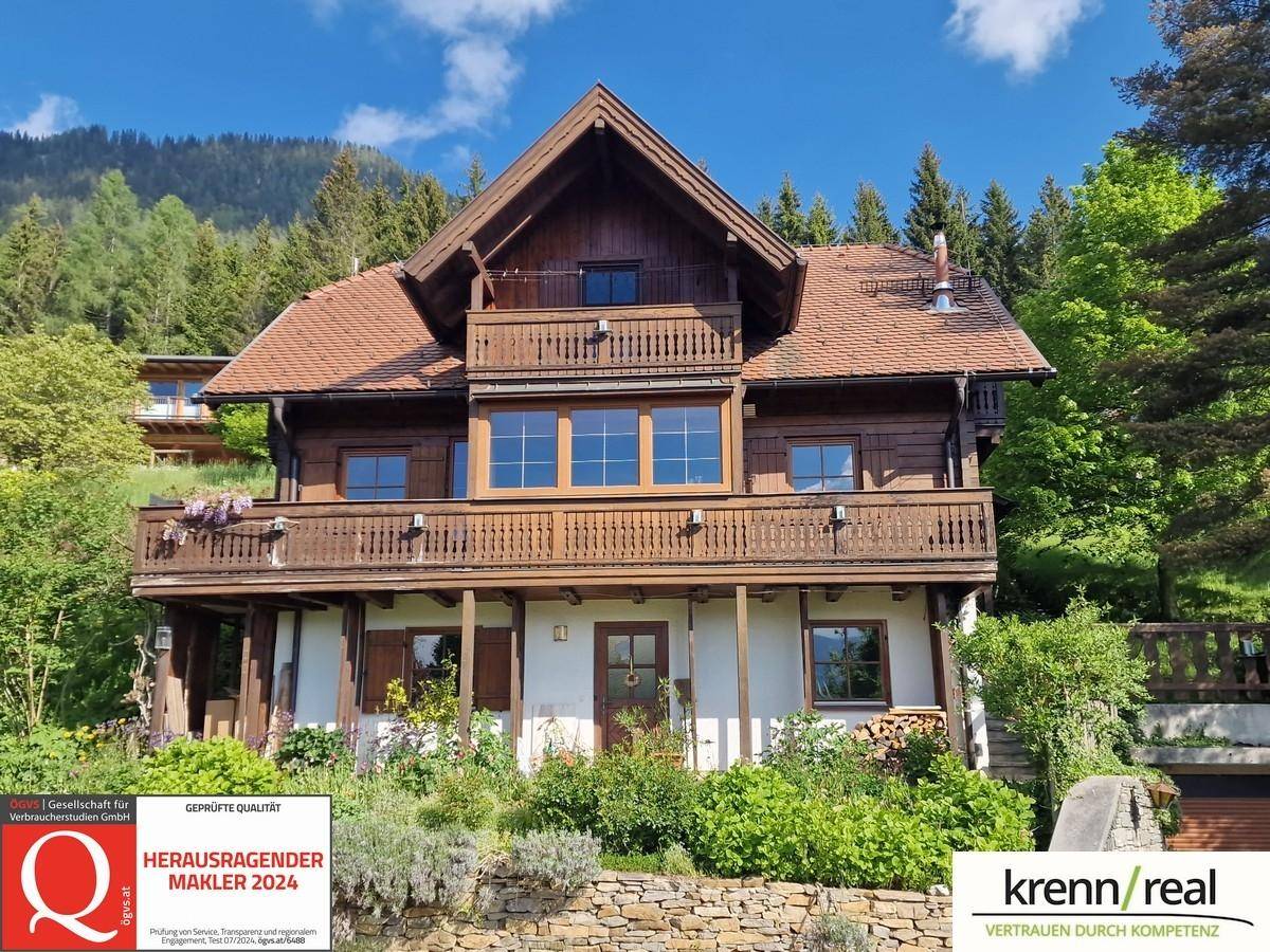 Traditionelles Holzhaus mit mehreren Balkonen und Bergblick in grüner Umgebung.
