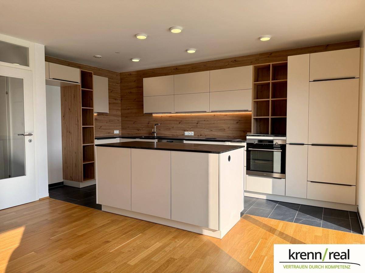 Moderne Einbauküche mit Kücheninsel, Holzakzenten und integriertem Backofen.