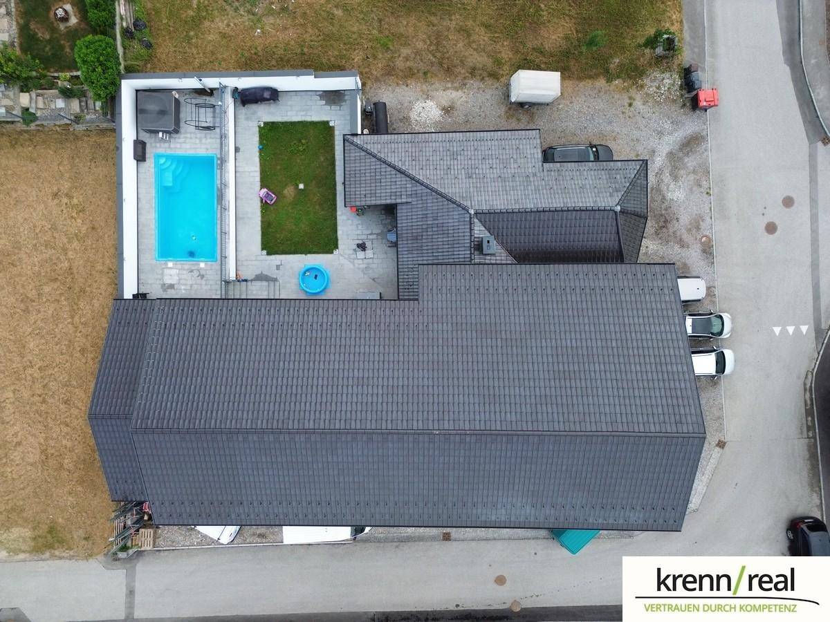 Draufsicht auf das Anwesen mit dunklem Dach, Swimmingpool und gepflegtem Außenbereich.