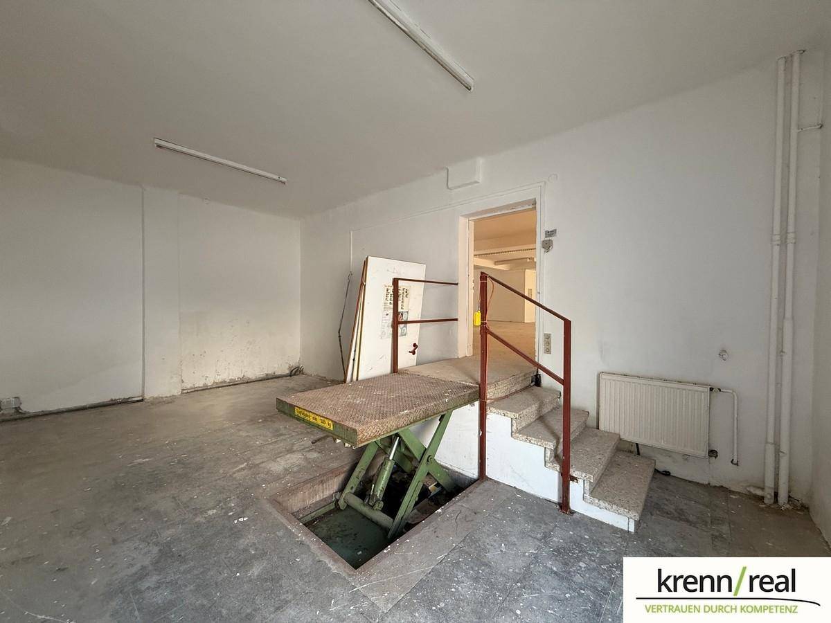 Funktionaler Raum mit einem Lastenaufzug und Treppe, ideal für Lagerung oder Warenlieferung im Untergeschoss.