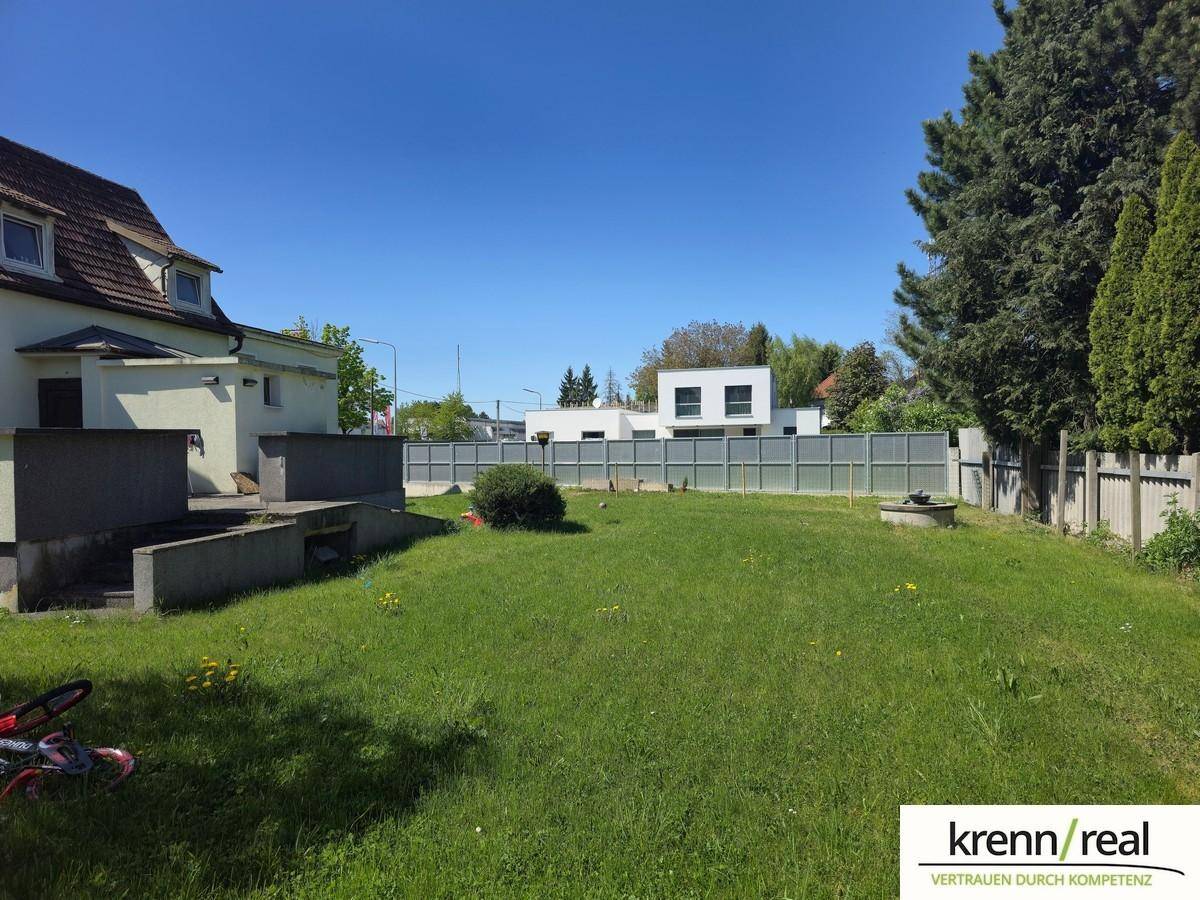 Großer, gepflegter Gartenbereich mit Rasenfläche und einer modernen Zaunanlage im Hintergrund.