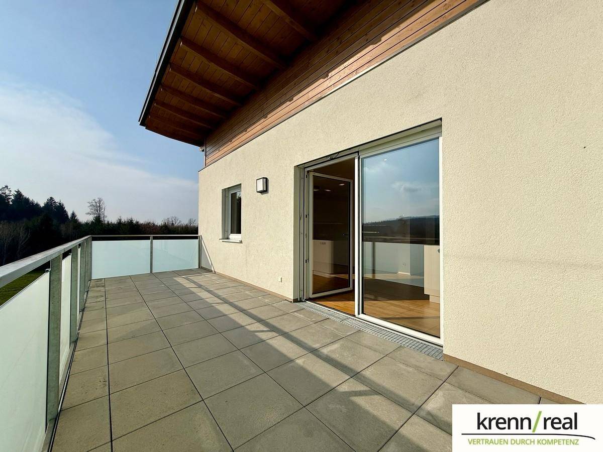 Geräumige Terrasse mit Fliesenboden und Glasgeländer, ideal für entspannte Stunden im Freien.