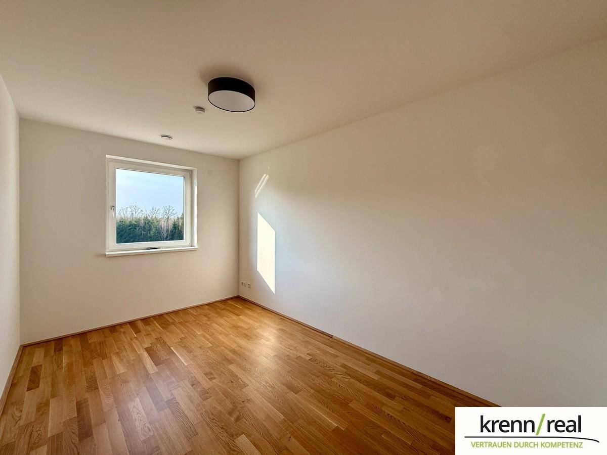 Lichtdurchflutetes Zimmer mit Holzboden und großem Fenster, ideal als Kinder- oder Gästezimmer.