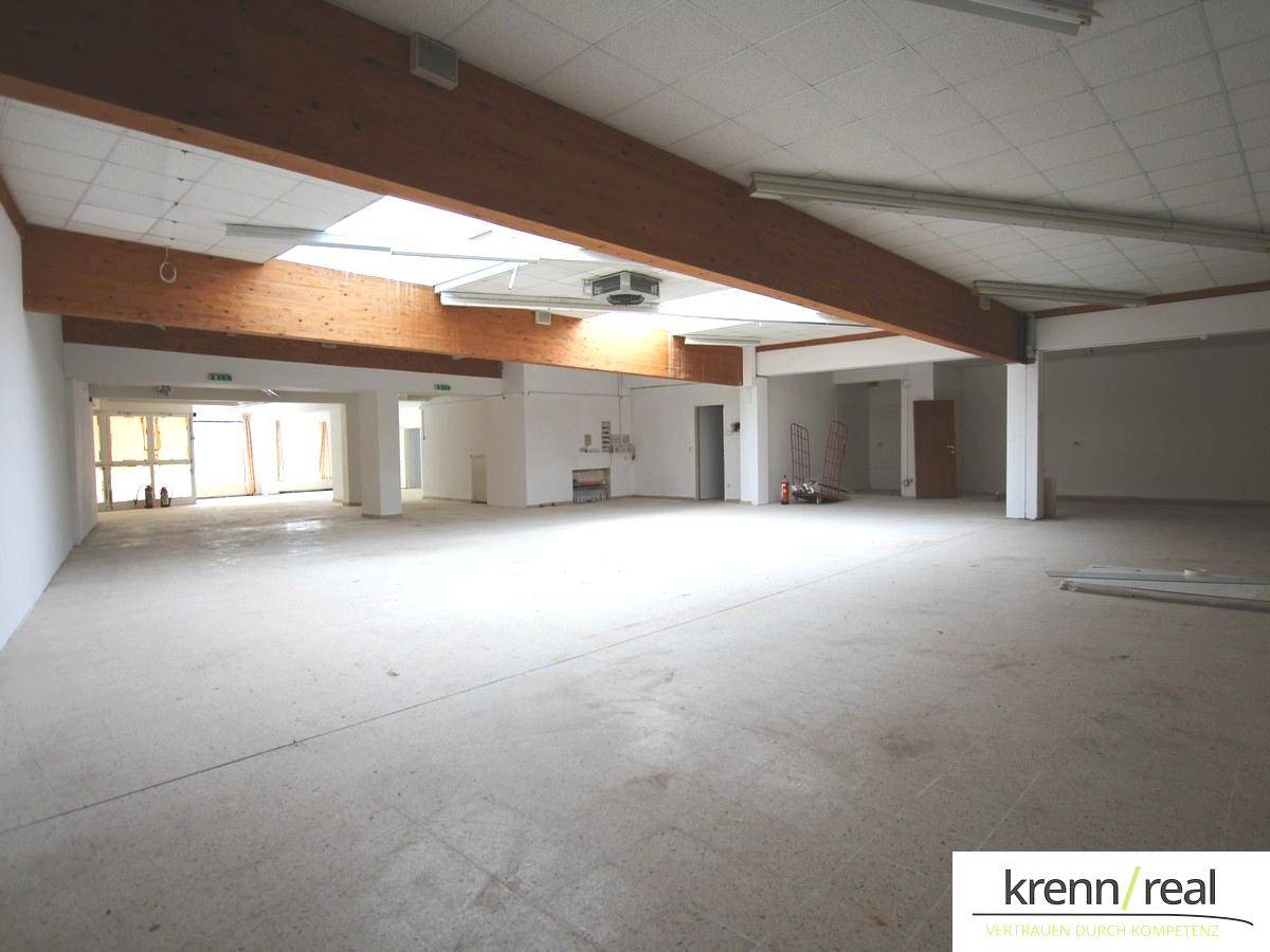 Weitläufiger Gewerberaum mit hohen Decken, Holzbalken und Oberlichtern, bereit für den Ausbau.