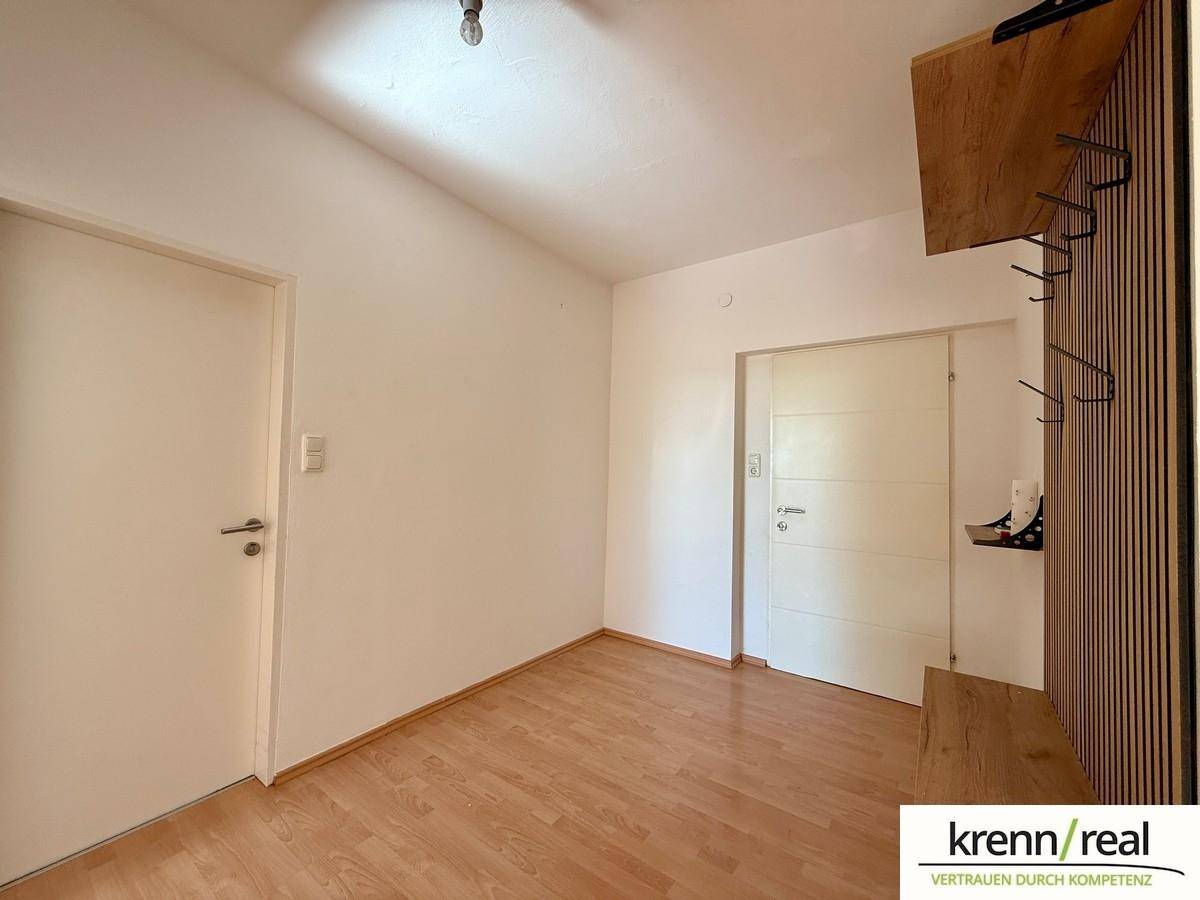 Leerer Raum mit Laminatboden und zwei Türen, bereit für individuelle Gestaltung.