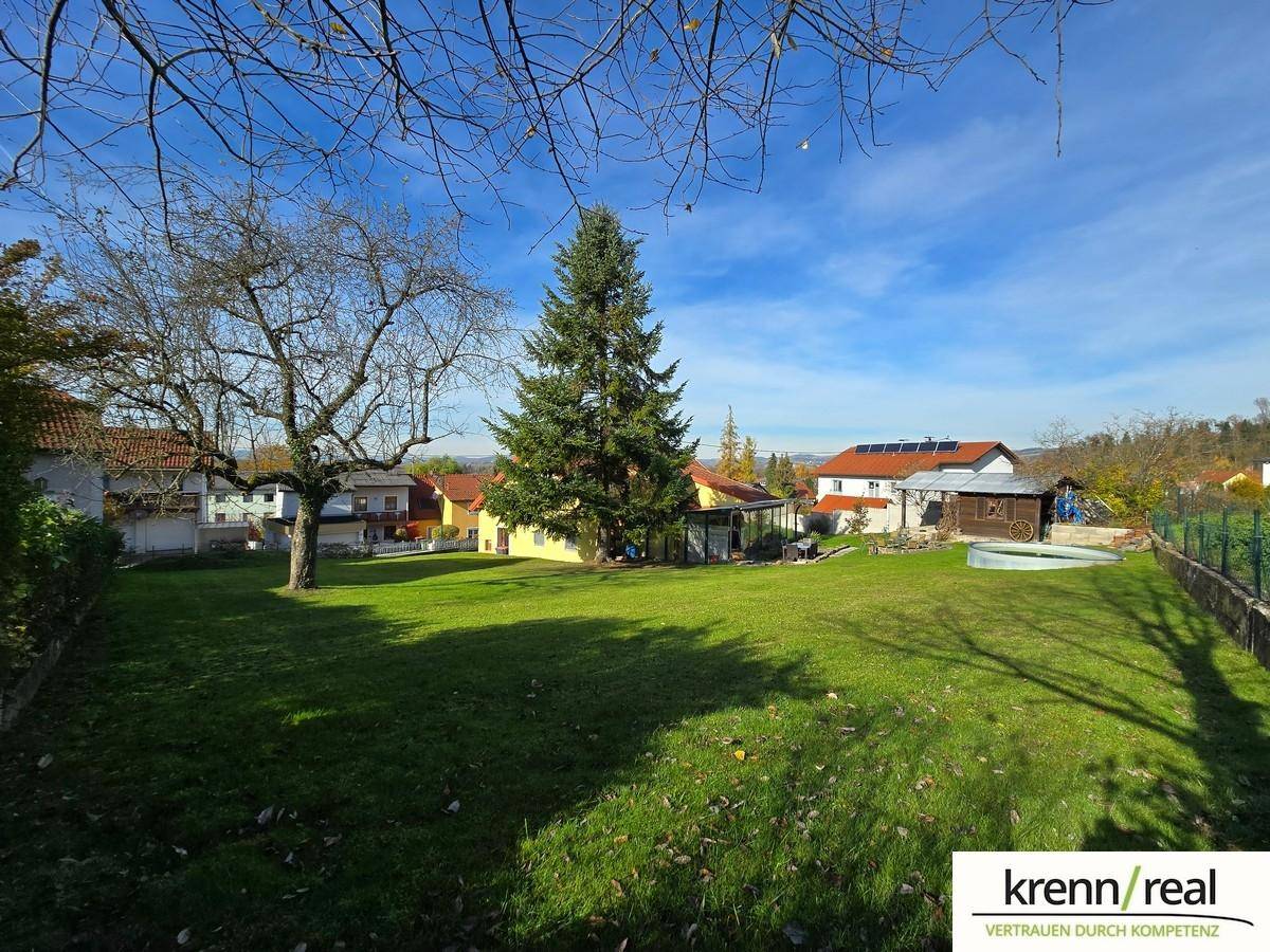 Großer, gepflegter Garten mit altem Baumbestand und Blick auf die umliegenden Wohnhäuser.