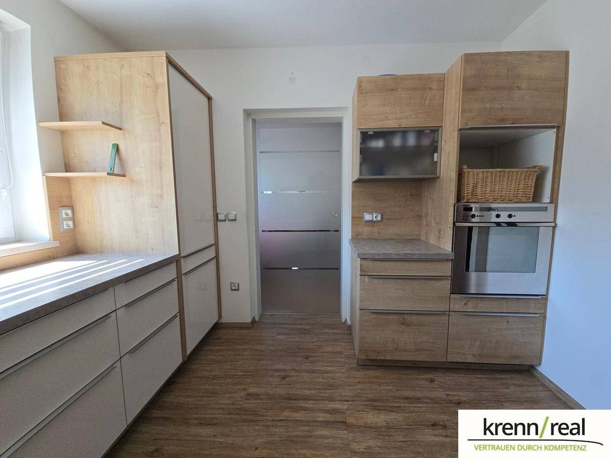Helle Küche mit modernen Holzschränken, integrierten Geräten und viel Arbeitsfläche.