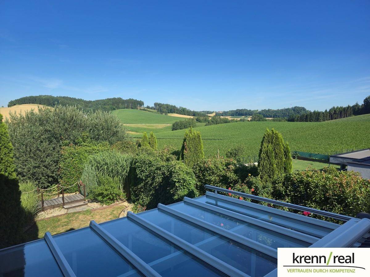 Weitläufiger Blick über grüne Hügel und Felder unter blauem Himmel.