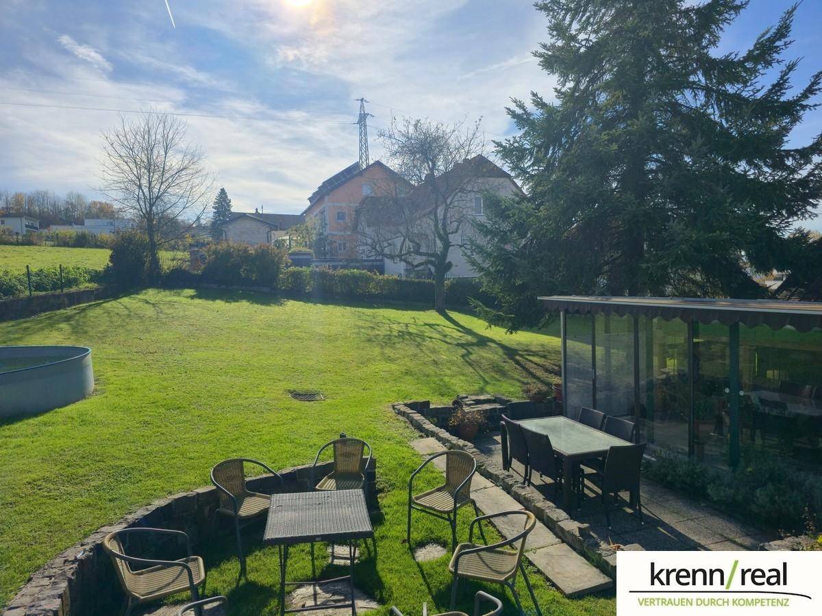 Gemütlicher Außenbereich mit Sitzgelegenheiten, Wintergarten und Blick auf den weitläufigen Garten.
