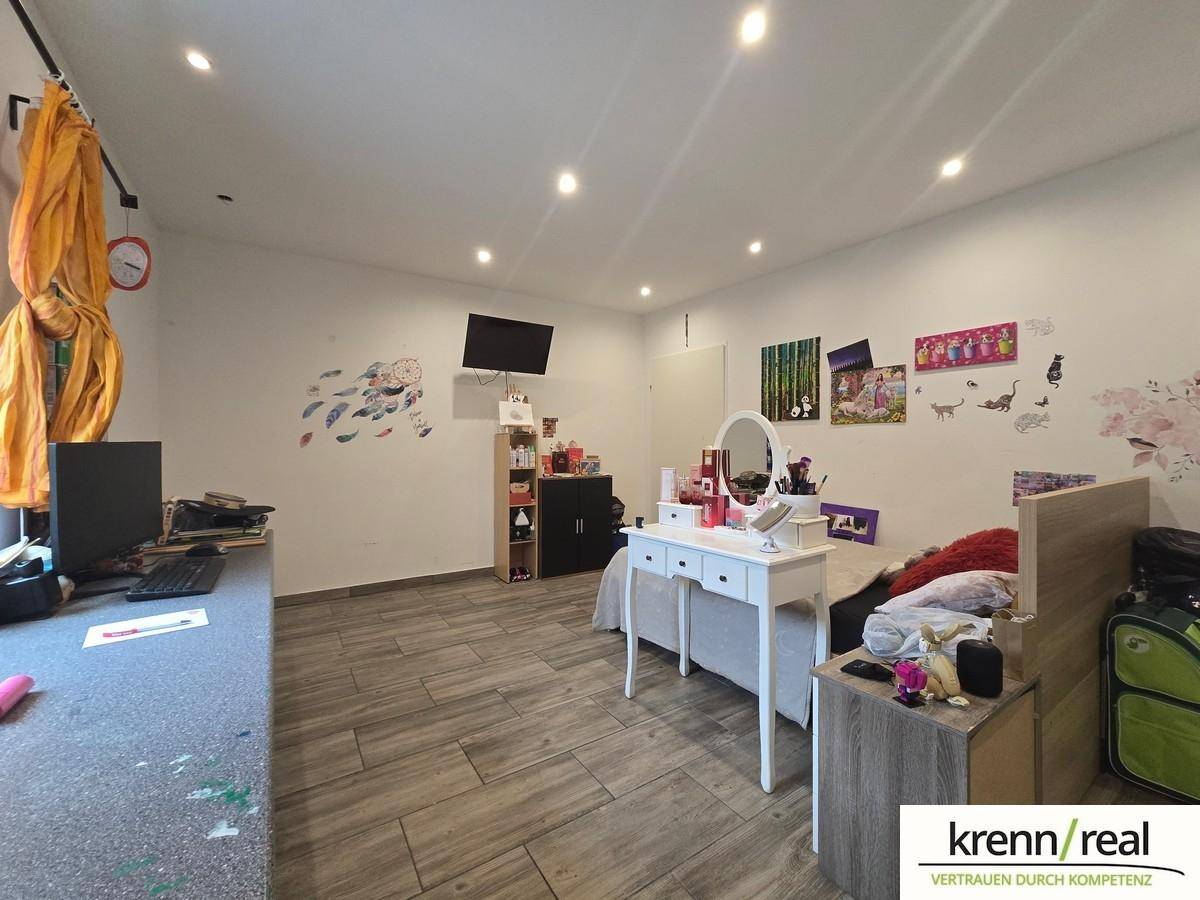 Helles Schlafzimmer mit Bett, Schminktisch und Schreibtischbereich, dekoriert mit Wandstickern.