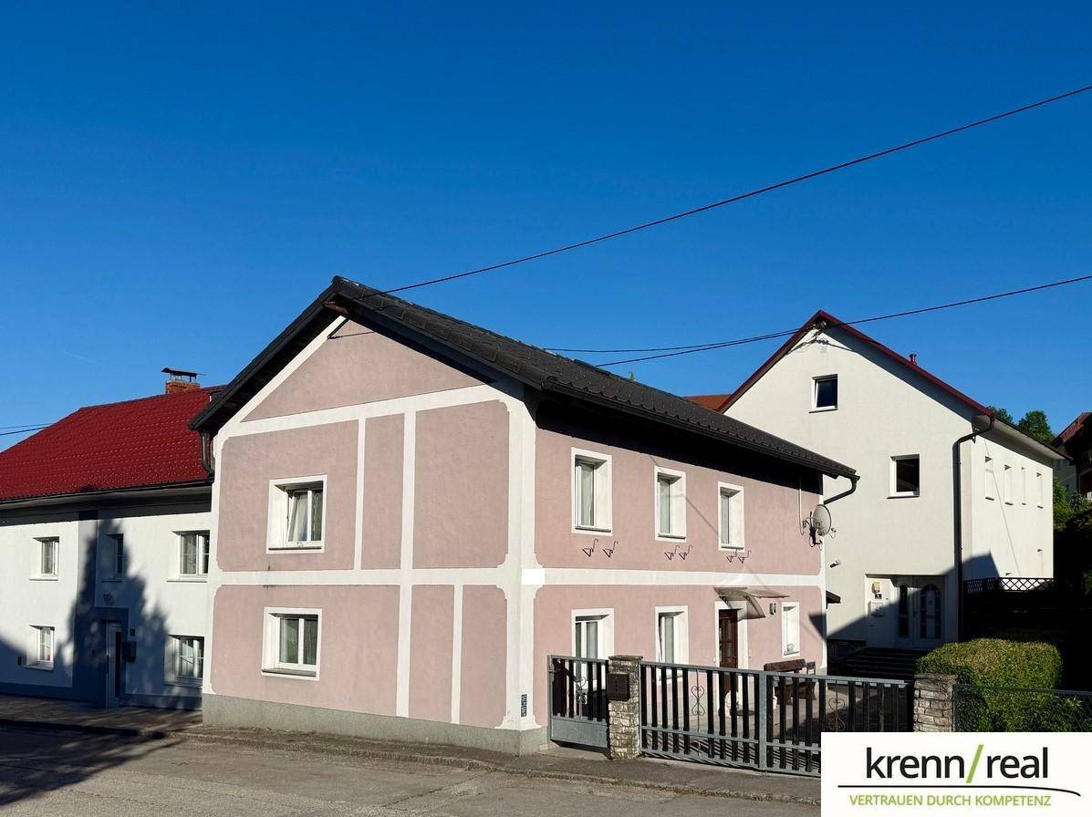 Ansicht der Hausfassade mit traditioneller Architektur und rosa-beiger Farbgebung unter klarem Himmel.