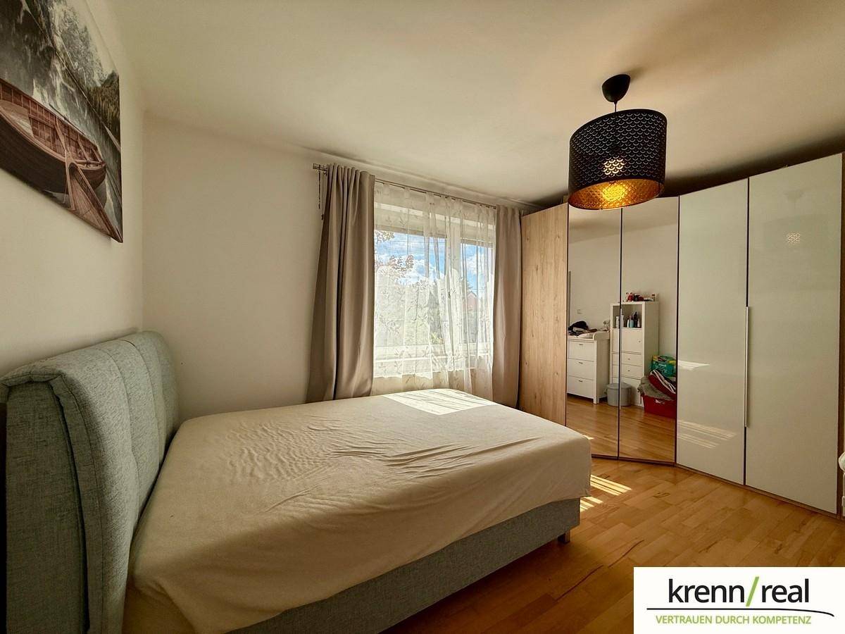 Schlafzimmer mit Doppelbett, großem Spiegelschrank und hellem Holzfußboden.