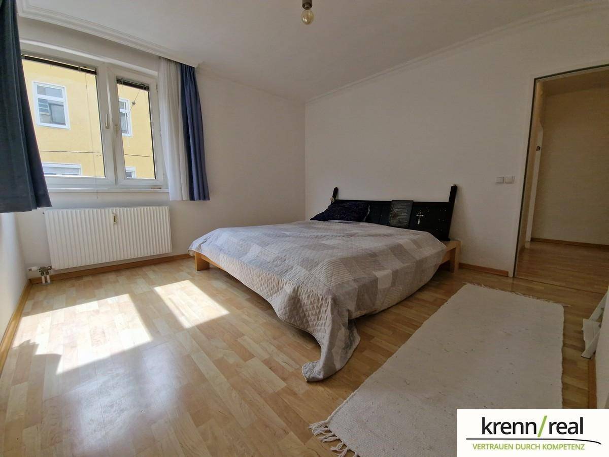 Helles Schlafzimmer mit Holzboden, großem Fenster und einem bequemen Doppelbett.