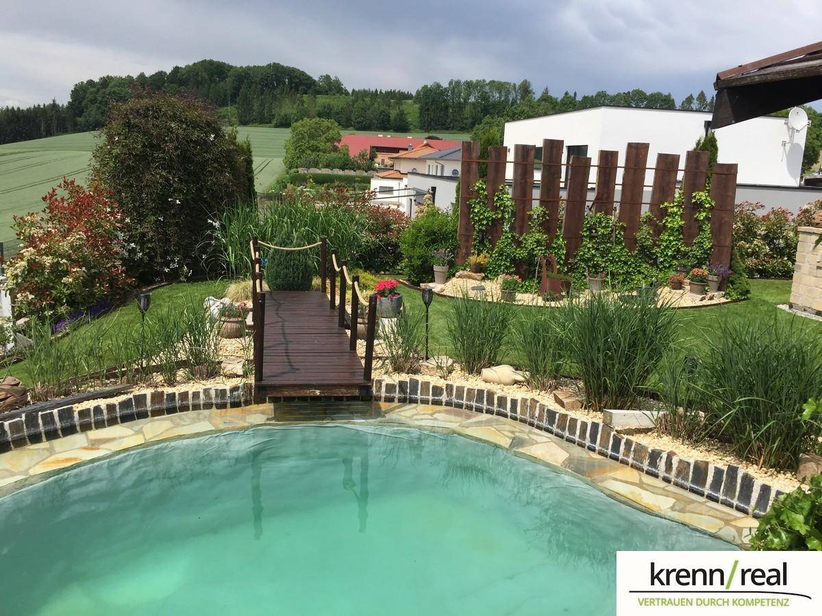 Gepflegter Gartenbereich mit Teich und weitem Blick auf die umliegende Landschaft.