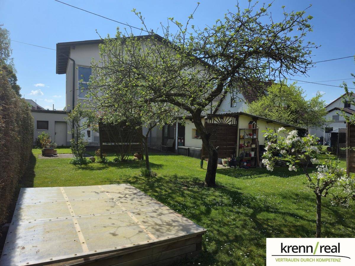 Gepflegter Gartenbereich mit Obstbäumen, Rasenfläche und einem kleinen Gartenhaus im Hintergrund.