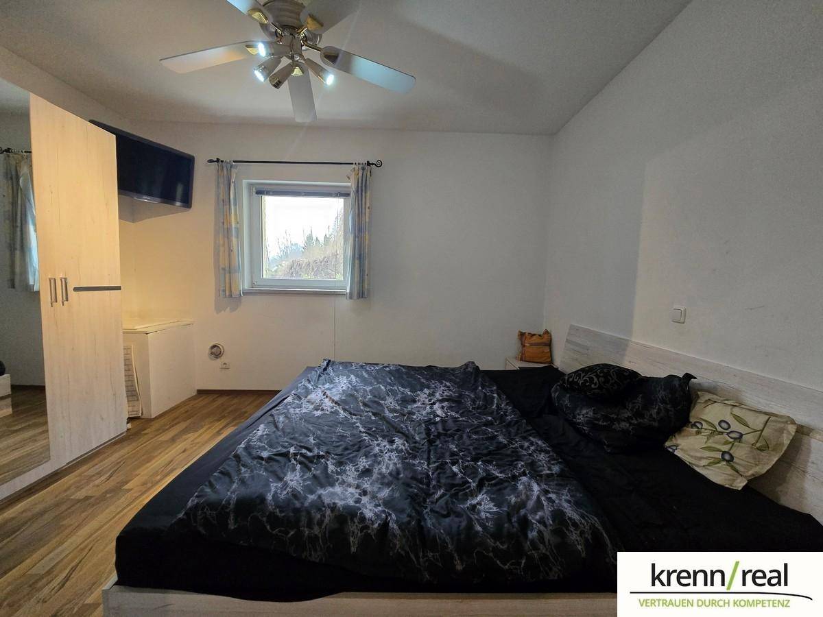 Gemütliches Schlafzimmer mit Doppelbett, Kleiderschrank, Fenster und einem Deckenventilator.