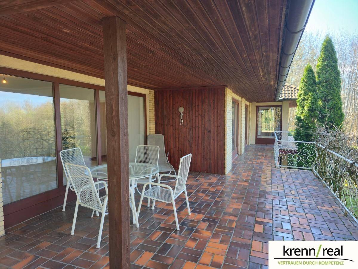 Überdachte Loggia mit Fliesenboden und Gartenmöbeln, ideal für entspannte Stunden im Freien.