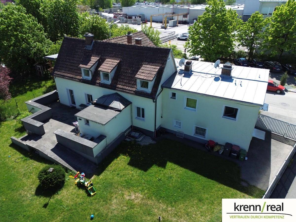 Luftaufnahme des Hauses mit Garten, angrenzenden Gebäuden und Parkplätzen in der Umgebung.
