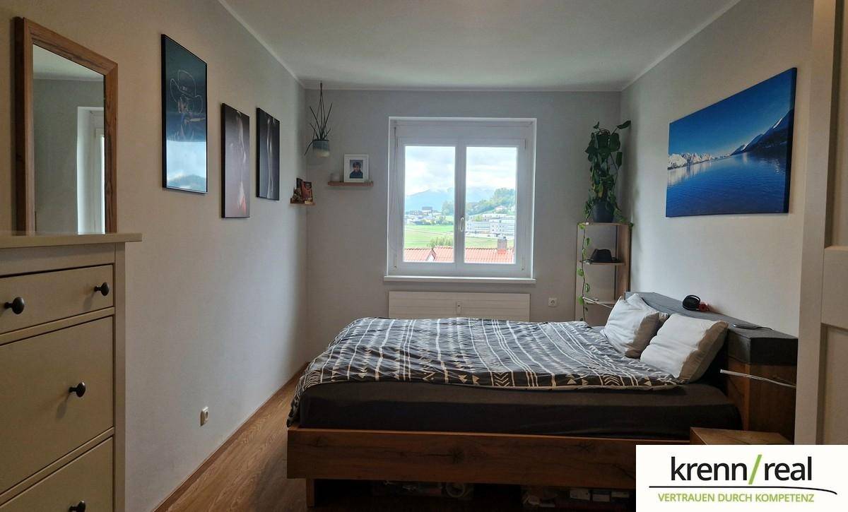Gemütliches Schlafzimmer mit Holzboden und großem Fenster, das einen schönen Ausblick bietet.