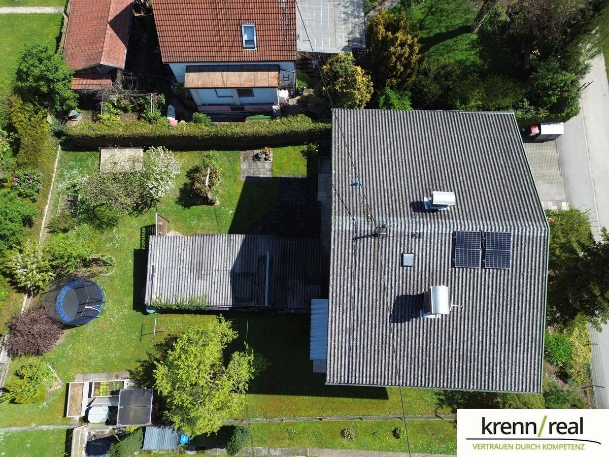 Luftaufnahme des Hauses mit Dach, Garten und angrenzenden Grundstücken bei Sonnenschein.