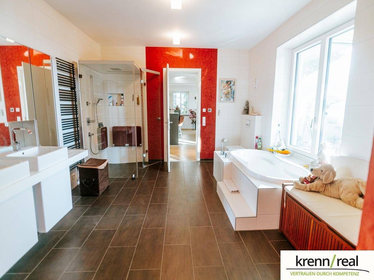 Geräumiges Badezimmer mit Badewanne, großer Dusche, Doppelwaschbecken und Fenster.