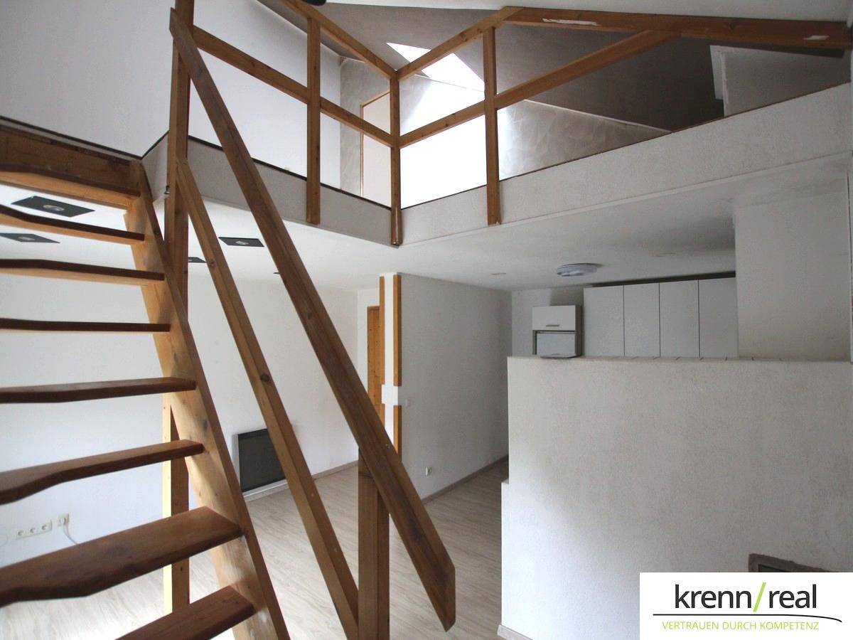 Rustikale Holztreppe führt zu einem offenen Galeriebereich, mit Blick auf den unteren Wohnbereich.