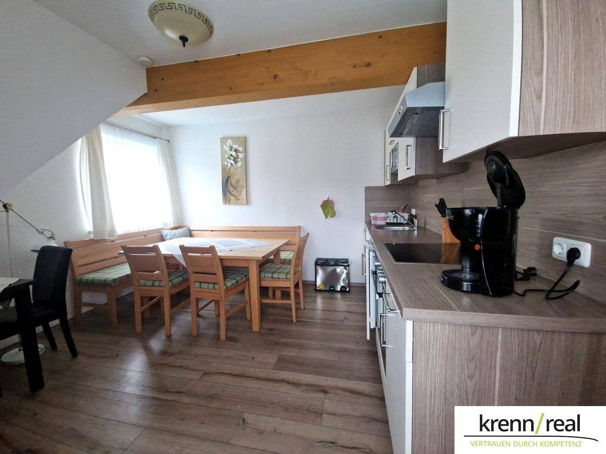 Funktionale Küche mit Essbereich, Holztisch und Dachschräge, ideal für gemeinsame Mahlzeiten.