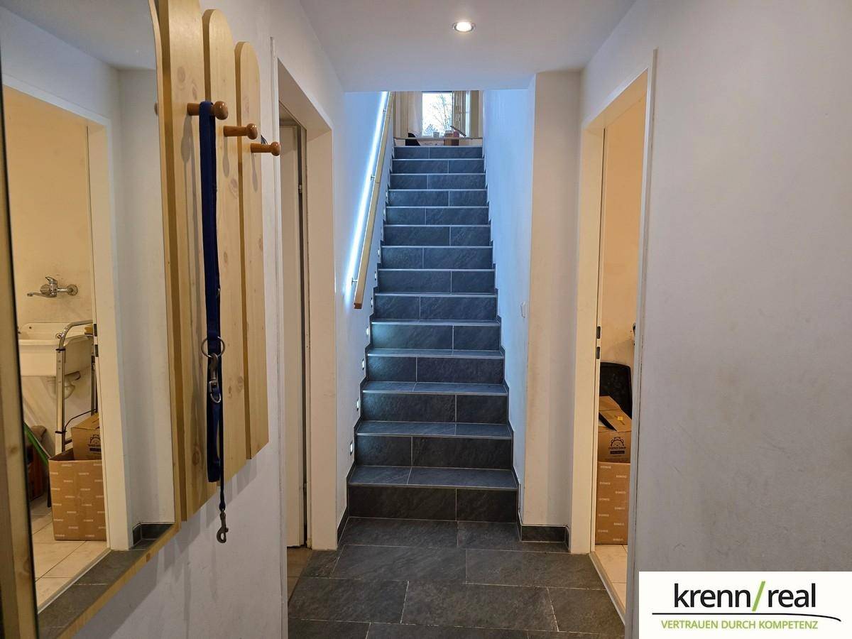 Heller Flur mit Treppe, die in das obere Stockwerk führt, und einem Spiegel an der Wand.