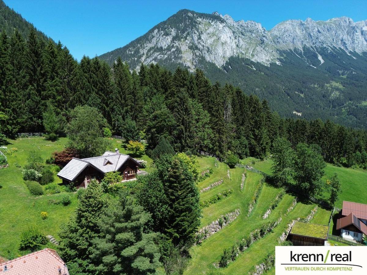 Panoramablick auf die terrassierte Landschaft mit weiteren Häusern, umgeben von dichtem Wald und majestätischen Bergen.