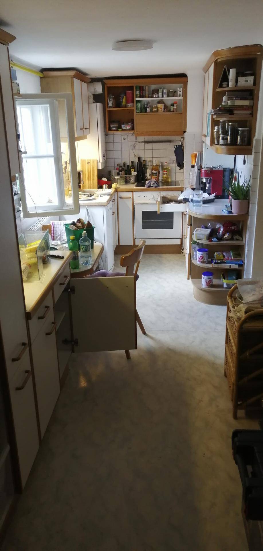 Helle Küche mit Holzschränken, Fenster und funktionaler Ausstattung.