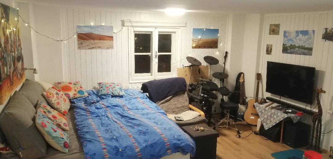 Schlafzimmer mit Bett, Musikinstrumenten und dekorativen Lichterketten.