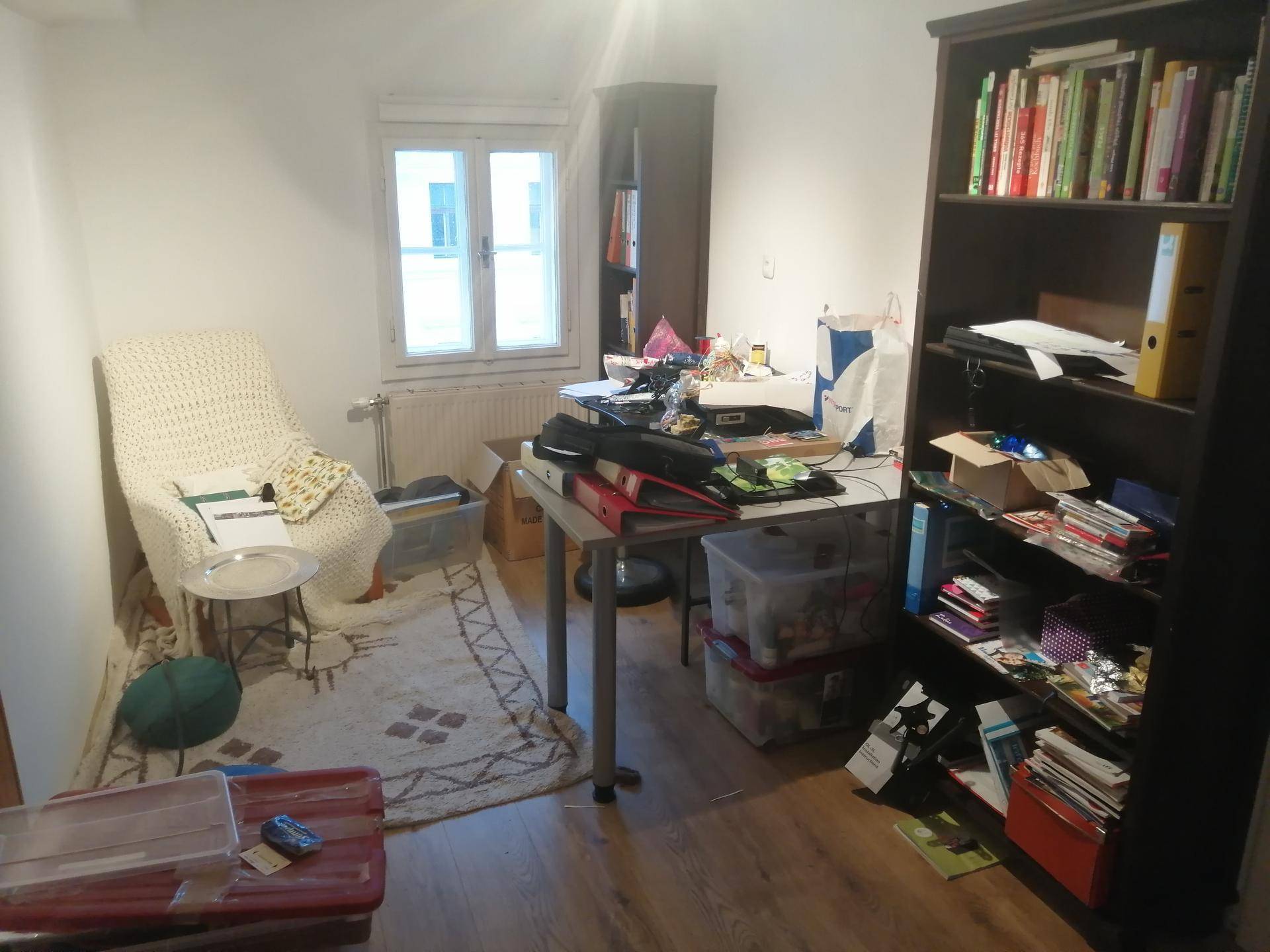 Arbeitszimmer mit Bücherregalen, Schreibtisch und Teppich.