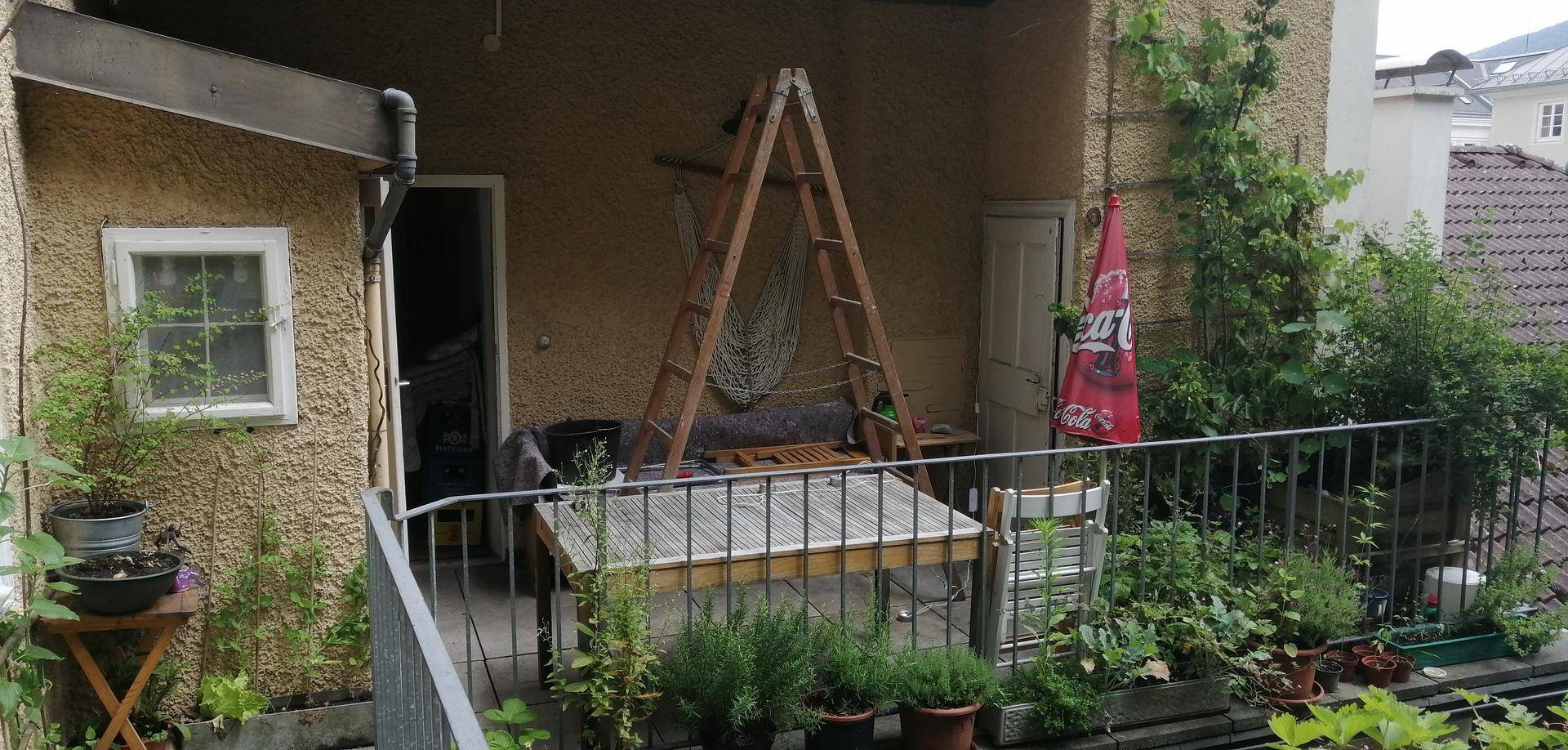 Balkon mit Pflanzen, Tisch und Blick auf die Umgebung.