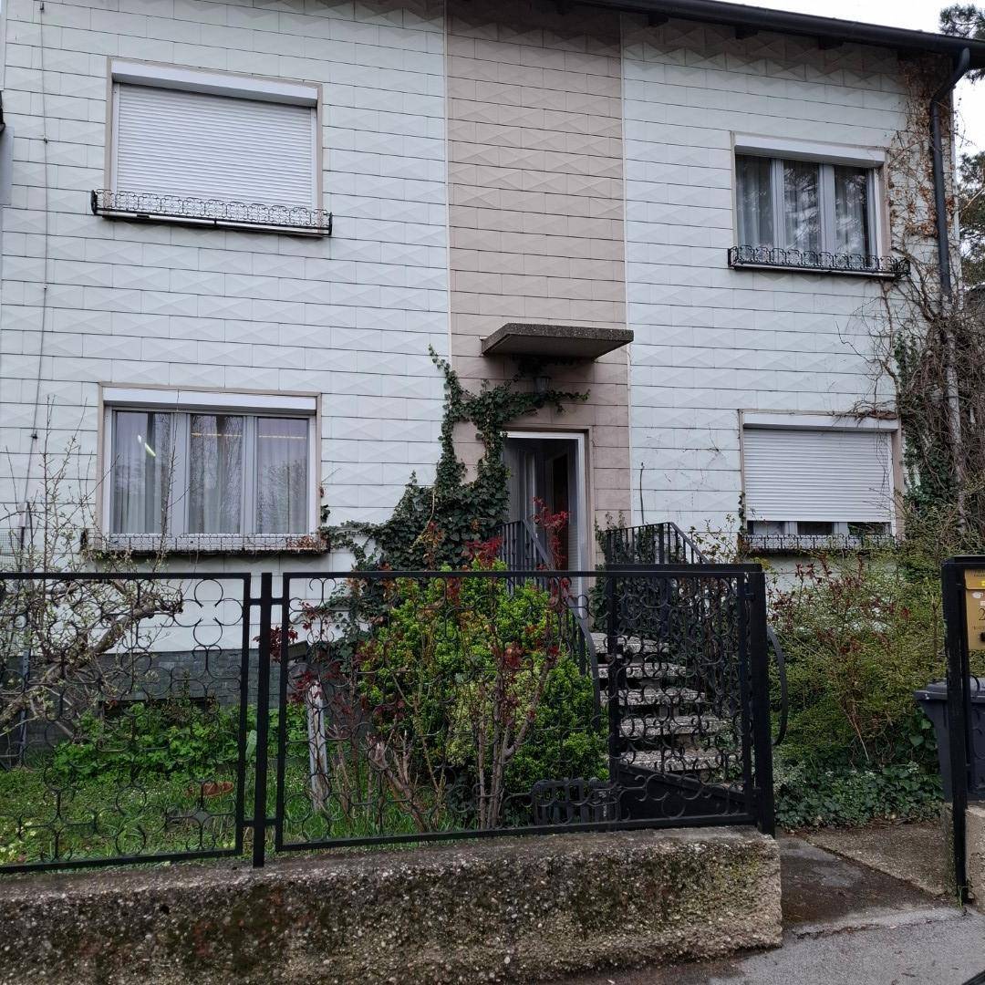 Vorderansicht des Hauses mit Rollläden an den Fenstern und gepflegter Bepflanzung.