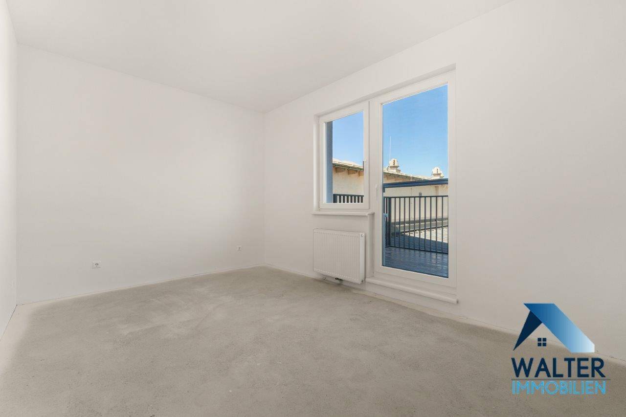 Heller, unmöblierter Raum mit weiß gestrichenen Wänden und Zugang zu einem Balkon.
