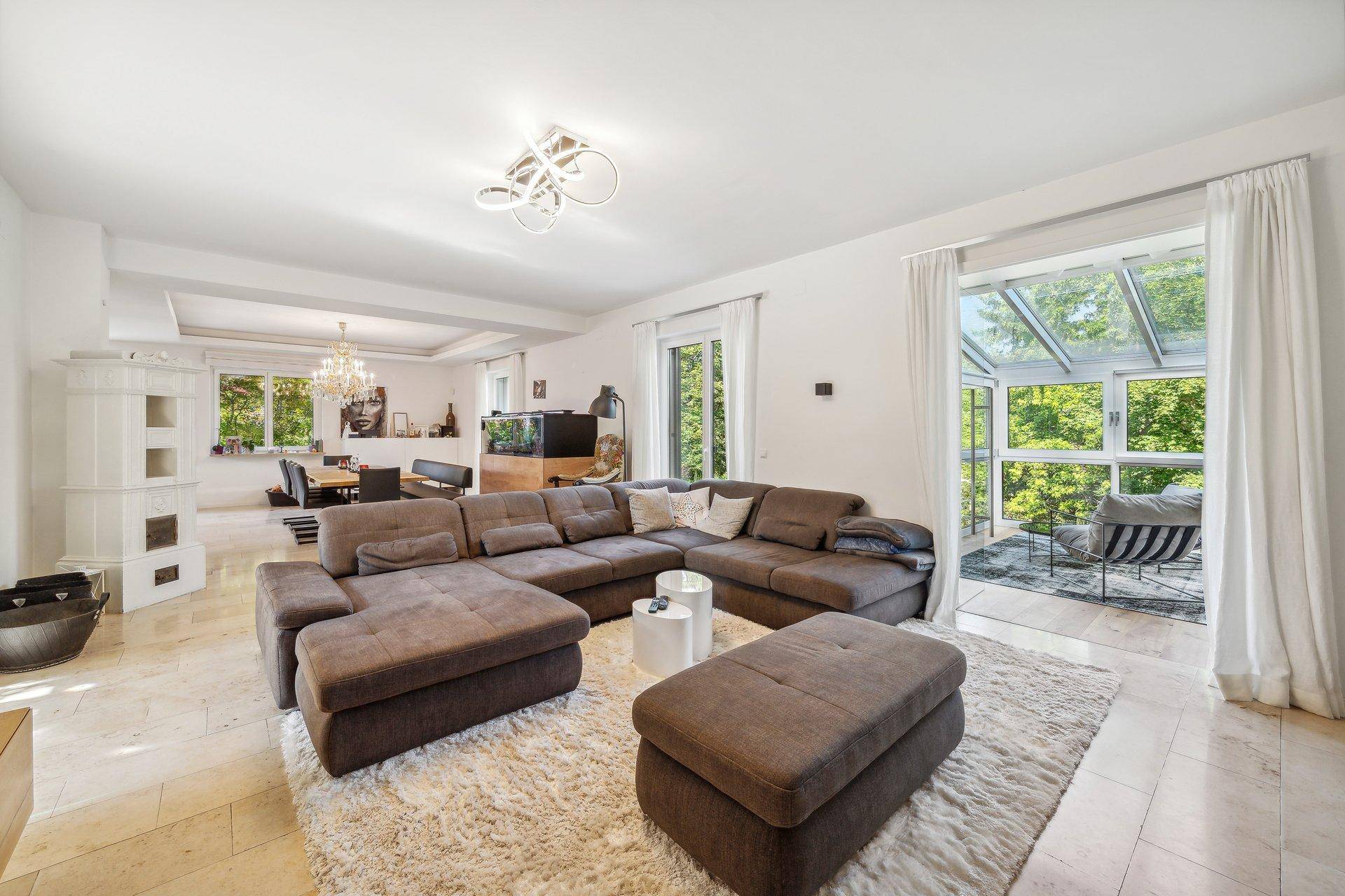 Geräumiges Wohnzimmer mit großem Sofa, offenem Essbereich und Zugang zum Wintergarten.