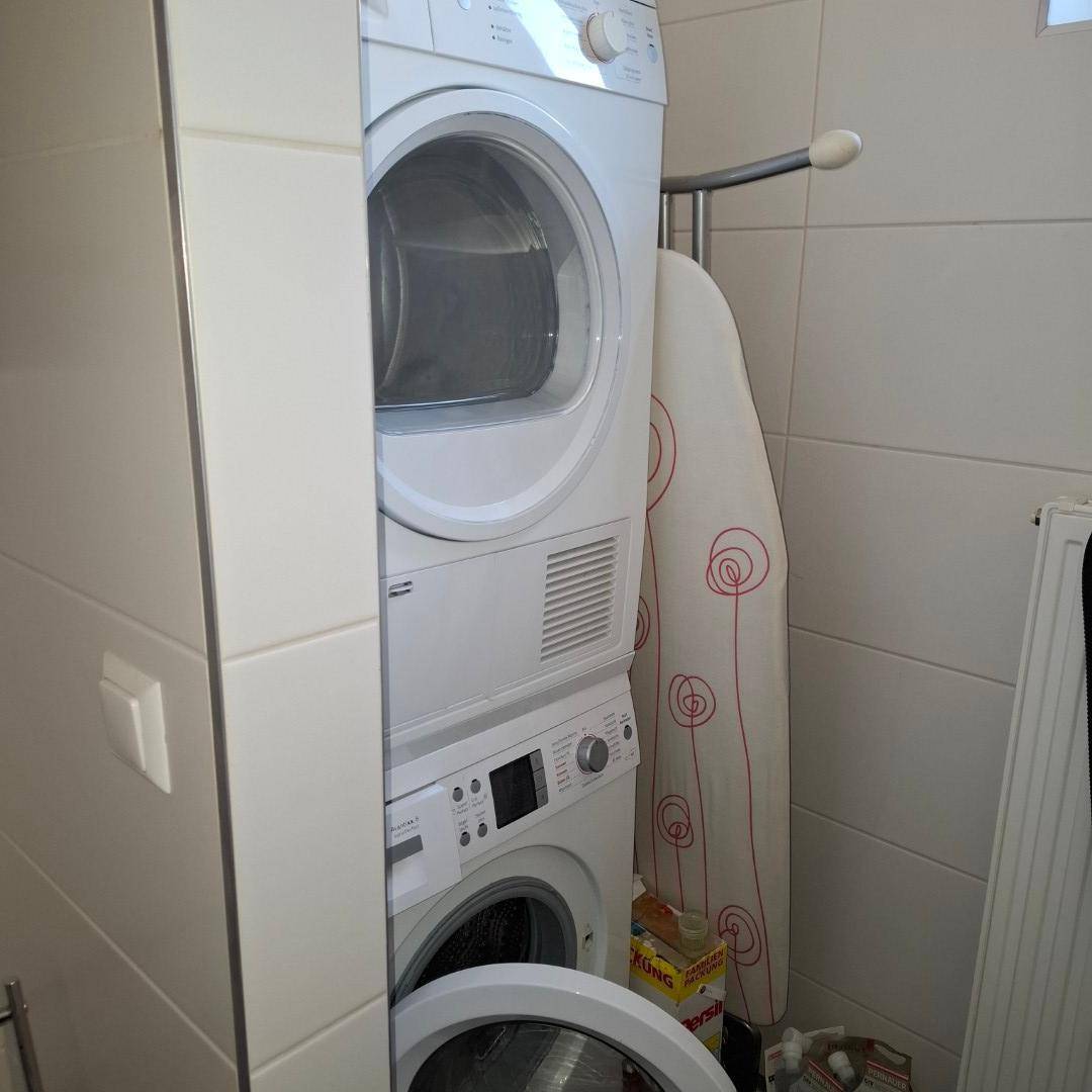 Übereinander gestapelte Waschmaschine und Trockner in einem praktischen Hauswirtschaftsraum, platzsparend installiert.