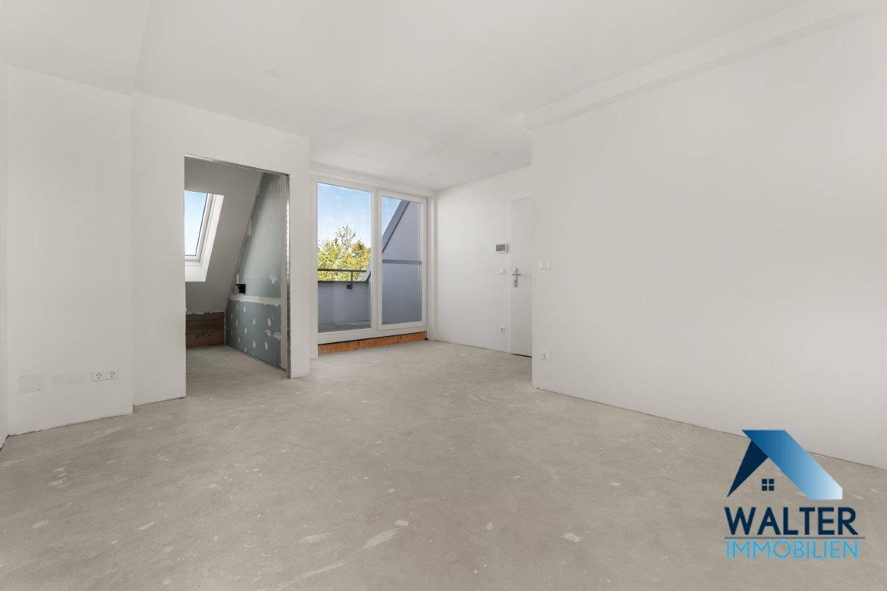 Großer, unmöblierter Wohnbereich mit Zugang zu einem Balkon und Dachfenstern im Hintergrund.