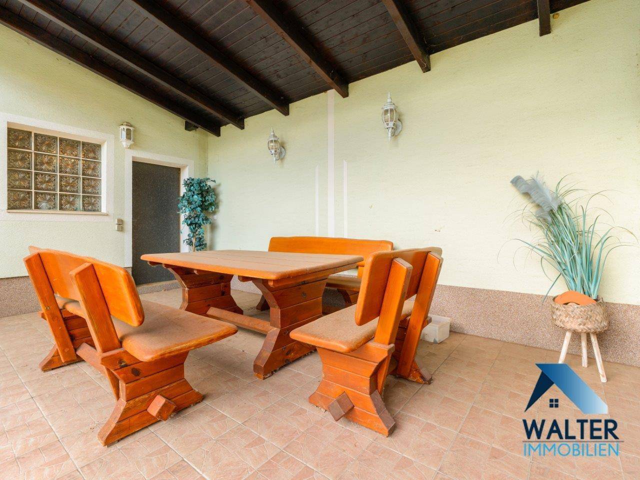 Überdachte Terrasse mit rustikalen Holzmöbeln, ideal für Mahlzeiten im Freien bei jedem Wetter.