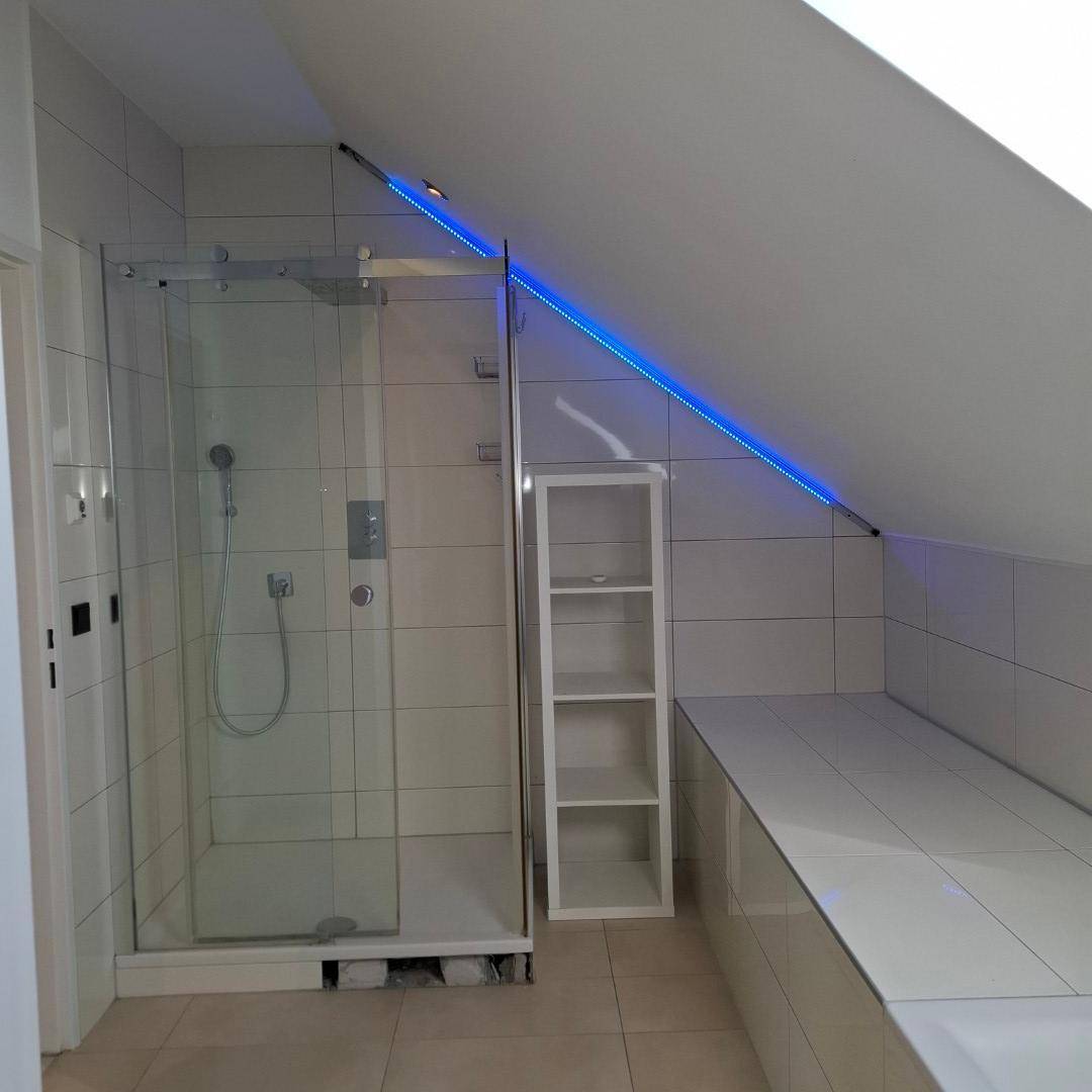 Modernes Badezimmer mit Duschkabine, Dachschräge und indirekter Beleuchtung in kühlem Blau.