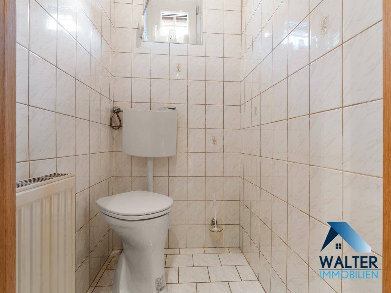 Kleines Gäste-WC mit weißen Fliesen und Fenster, funktional und hell gestaltet.