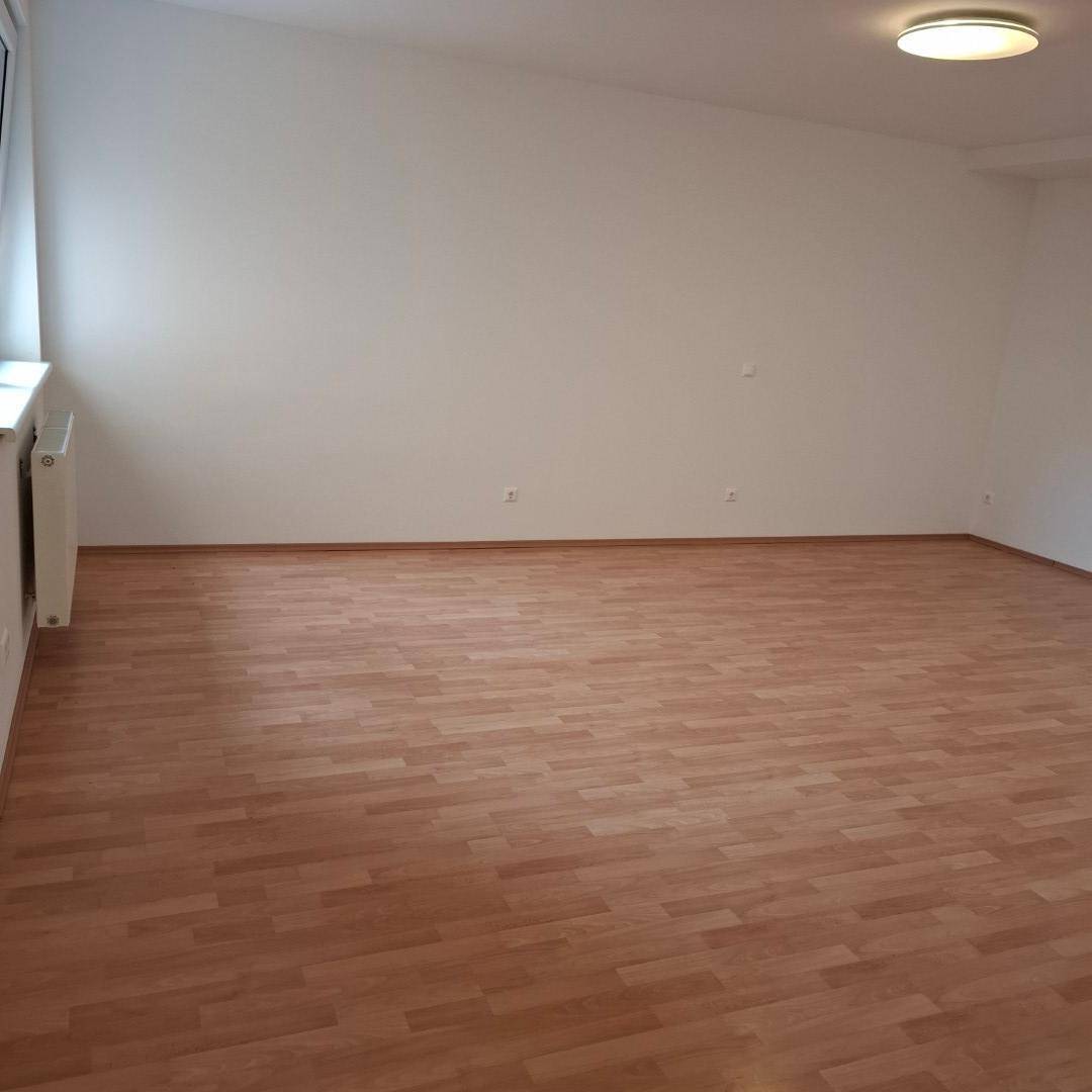 Geräumiger, leerer Raum mit Laminatboden, weißen Wänden und einem Fenster, ideal als Schlafzimmer.
