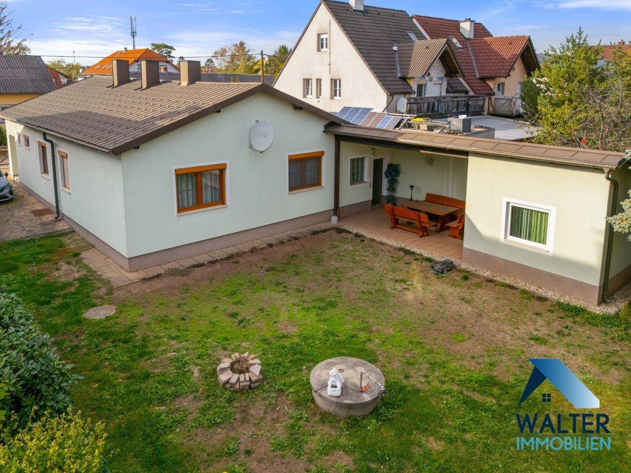 Hinterhof mit überdachter Terrasse und Rasenfläche, ideal für entspannte Stunden im Freien.