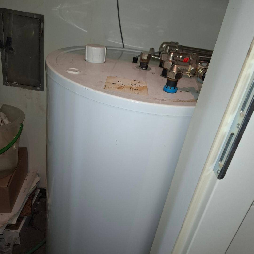 Großer weißer Warmwasserspeicher in einem praktischen Abstellraum, der für die Warmwasserversorgung sorgt.