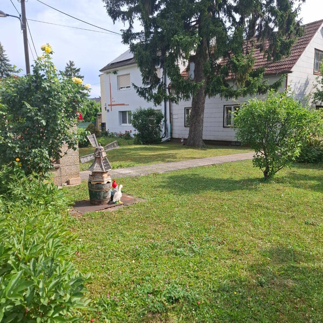 Vorgarten mit einem dekorativen Windmühlen-Element, Gartenzwergen und einem gepflasterten Weg zum Haus.