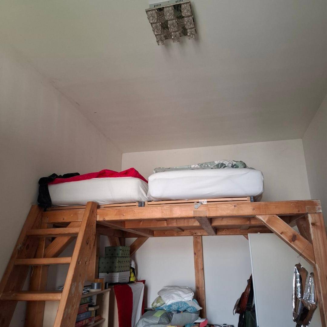 Schlafzimmer mit einem hölzernen Hochbett, das zusätzlichen Stauraum darunter bietet und den Raum optimal nutzt.