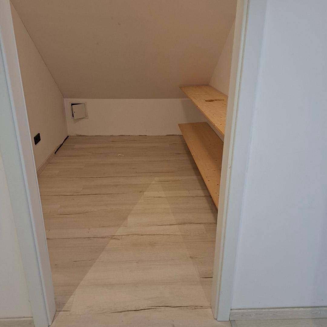 Praktischer Abstellraum im Dachgeschoss mit Dachschräge, Regalen und hellem Boden.