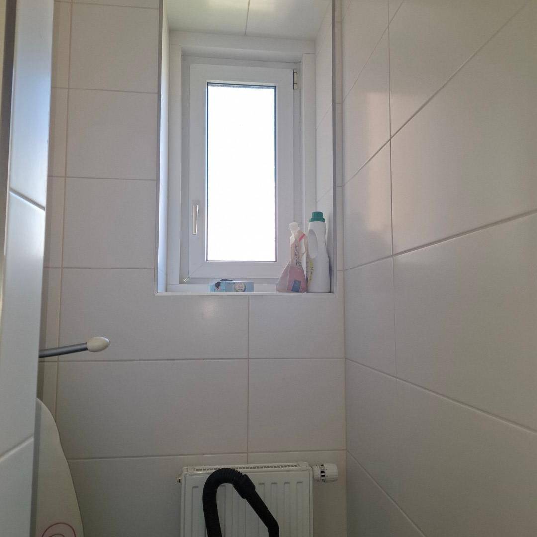 Helles Fenster in einem gefliesten Hauswirtschaftsraum, das für Tageslicht sorgt und den Raum erhellt.