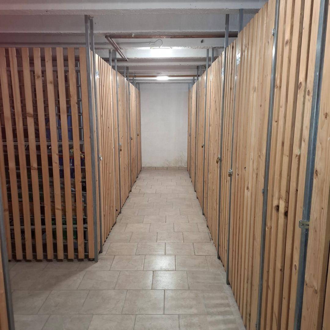 Kellerflur mit individuellen Lagerabteilen aus Holzlatten und Fliesenboden.